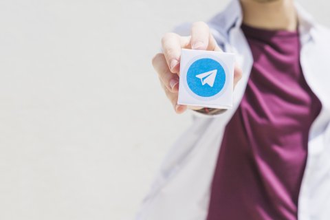 mano di una persona che tiene un blocco con logo telegram